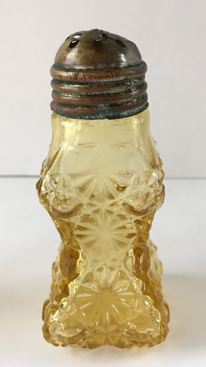 Amber coloured antique glass shaker with a lid with a rounded lid.