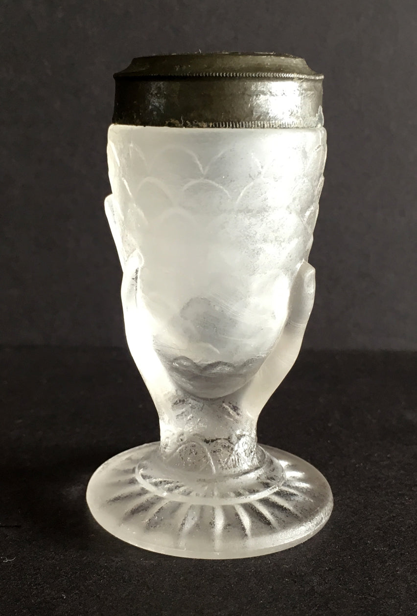 Close-up of a pressed glass salt shaker with a hand holding corn design.