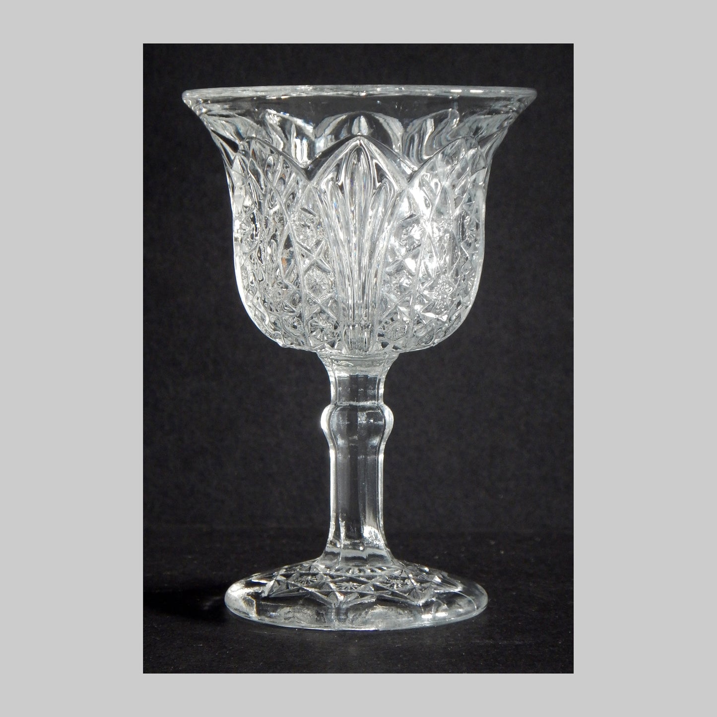 Antique flared clear glass cordial with arrowhead style design.