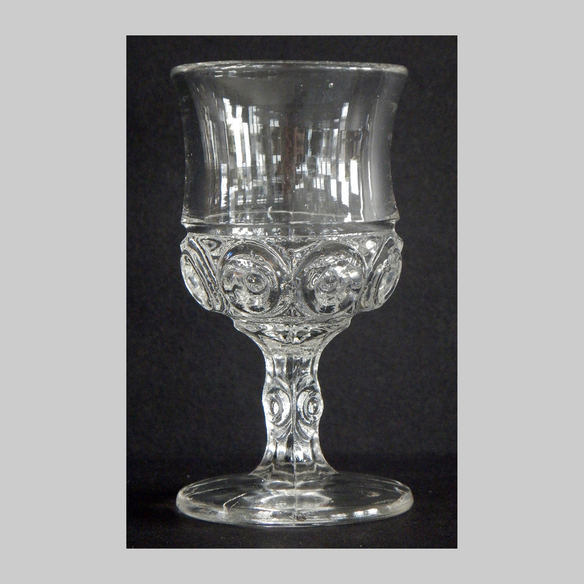 Antique clear glass cordial with sunken circles all around the cup and stem.