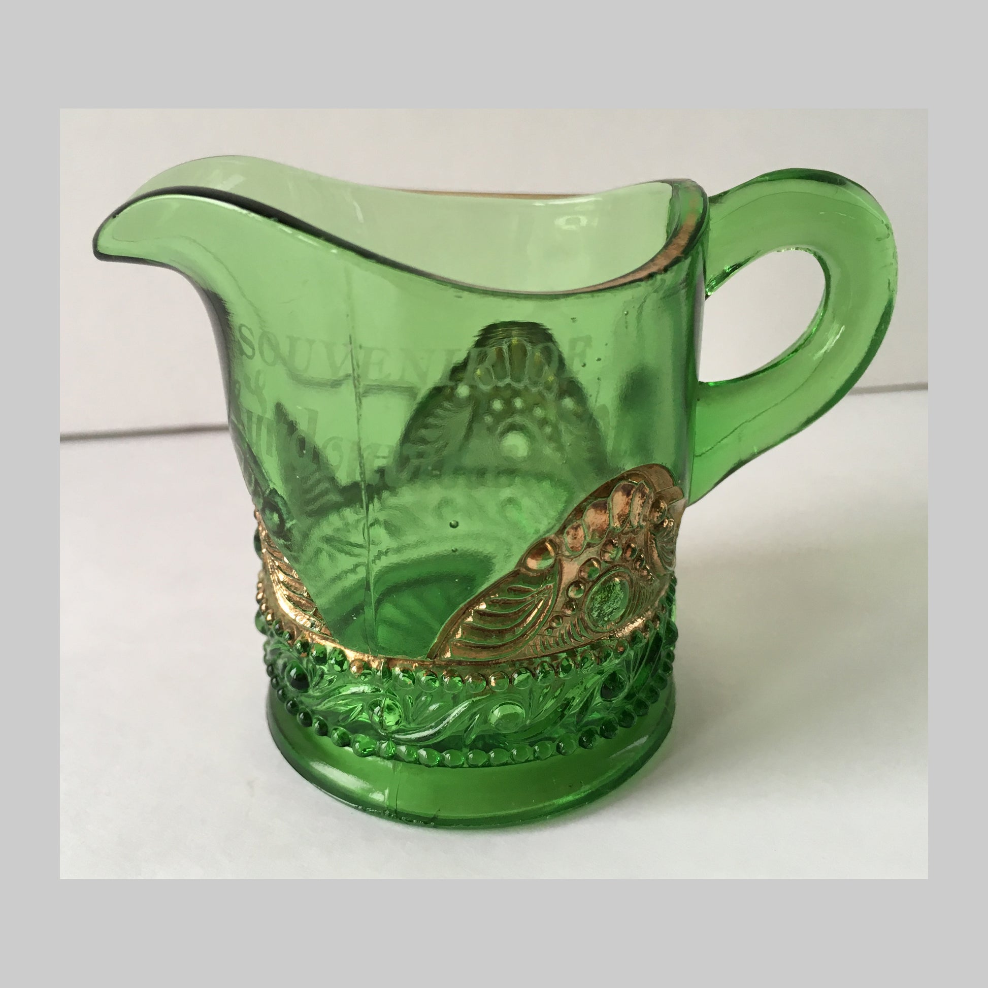 Antique green pressed glass creamer with gold bejewelled scallops around the base.