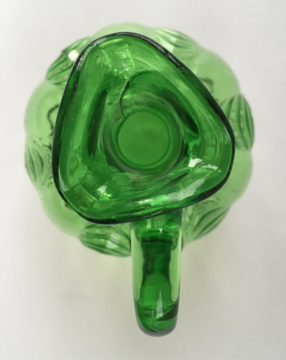 Looking from above at the mouth and handle of an antique green glass cruet. 