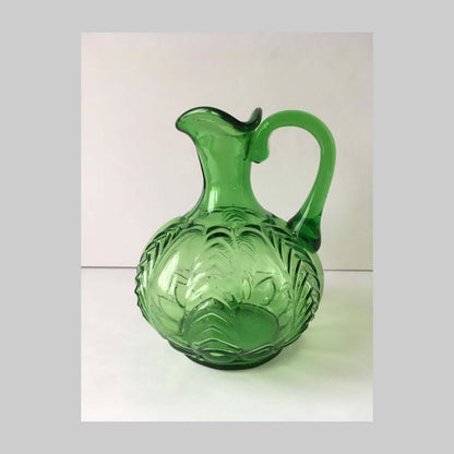 Antique pressed green glass cruet with handle with Florida pattern and edges.