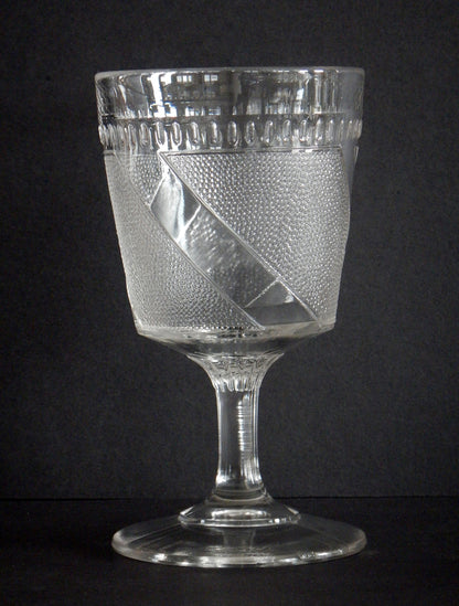 Close-up diagonal band and details on a clear pattern glass goblet.     