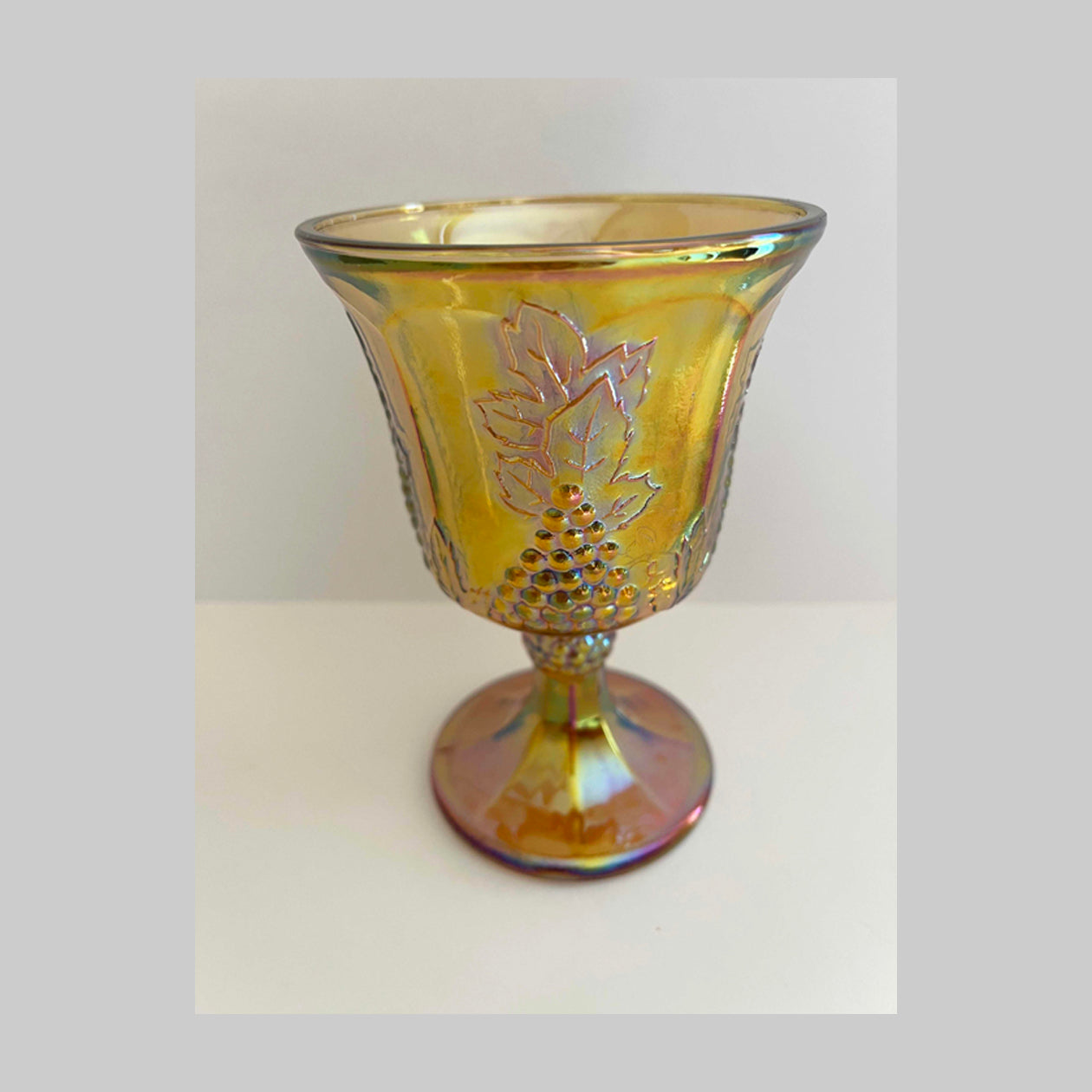 Vintage Carnival glass goblet, in iridescent gold, Harvest pattern with grapes and vine.