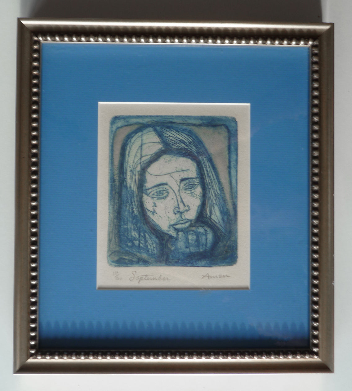 Framed edges showing, a blue etching printed by Irving Amen, of a pensive girl. 