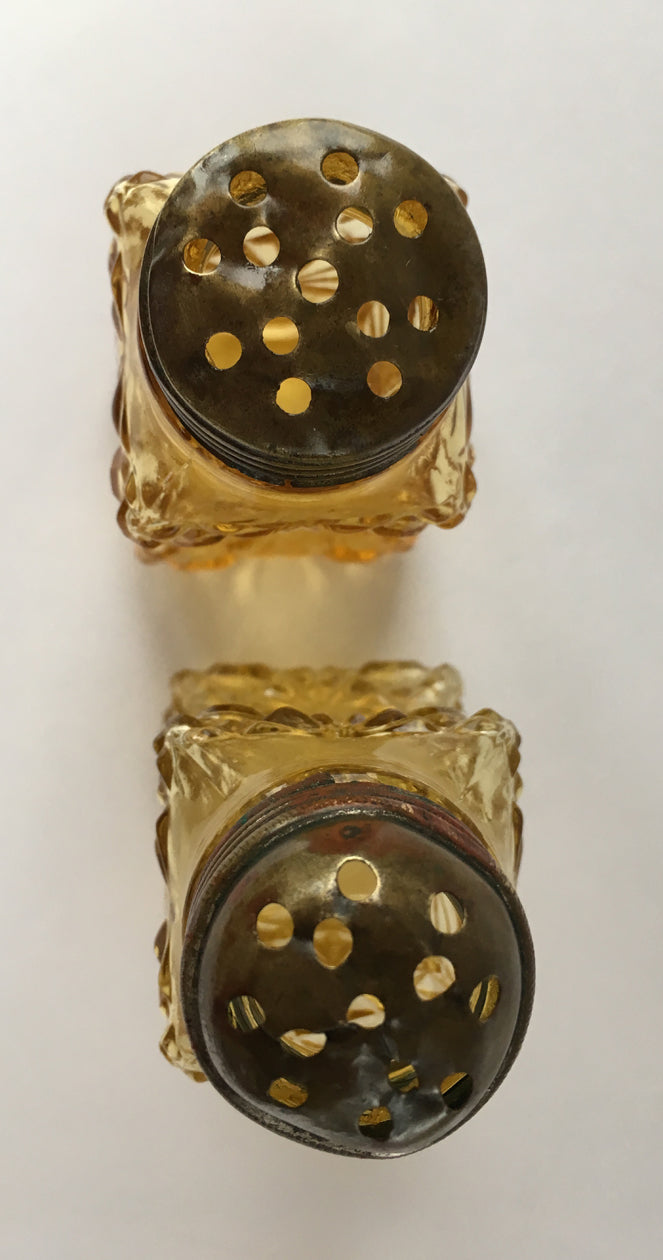 Looking from above at a the lids of a pair of amber glass shakers. 