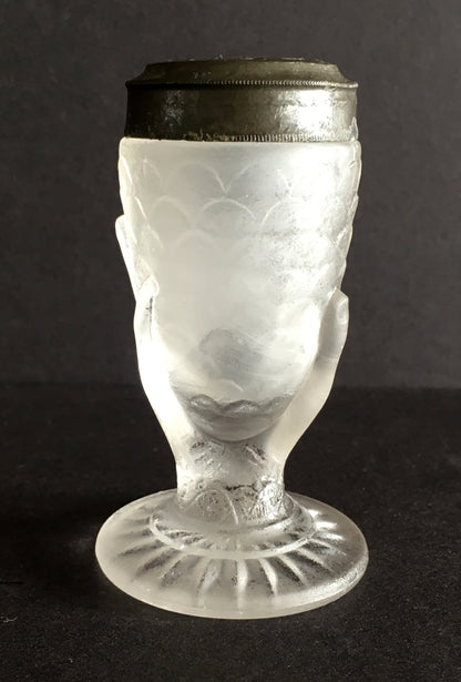 Close-up of a pressed glass salt shaker with a hand holding corn design. 