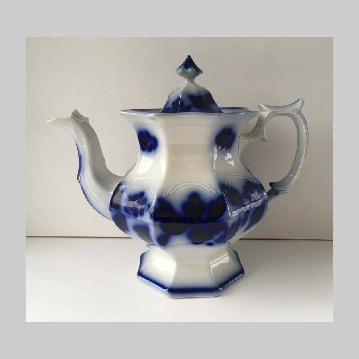 Antique flow blue ironstone teapot in Blueberry pattern in blue and white.