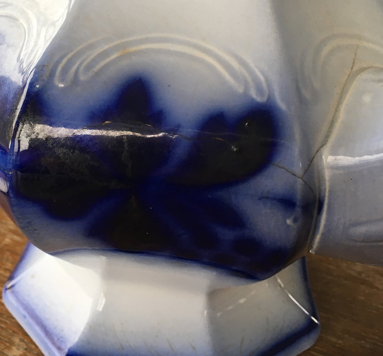 Close-up of repair of flow blue ironstone teapot in Blueberry pattern. 