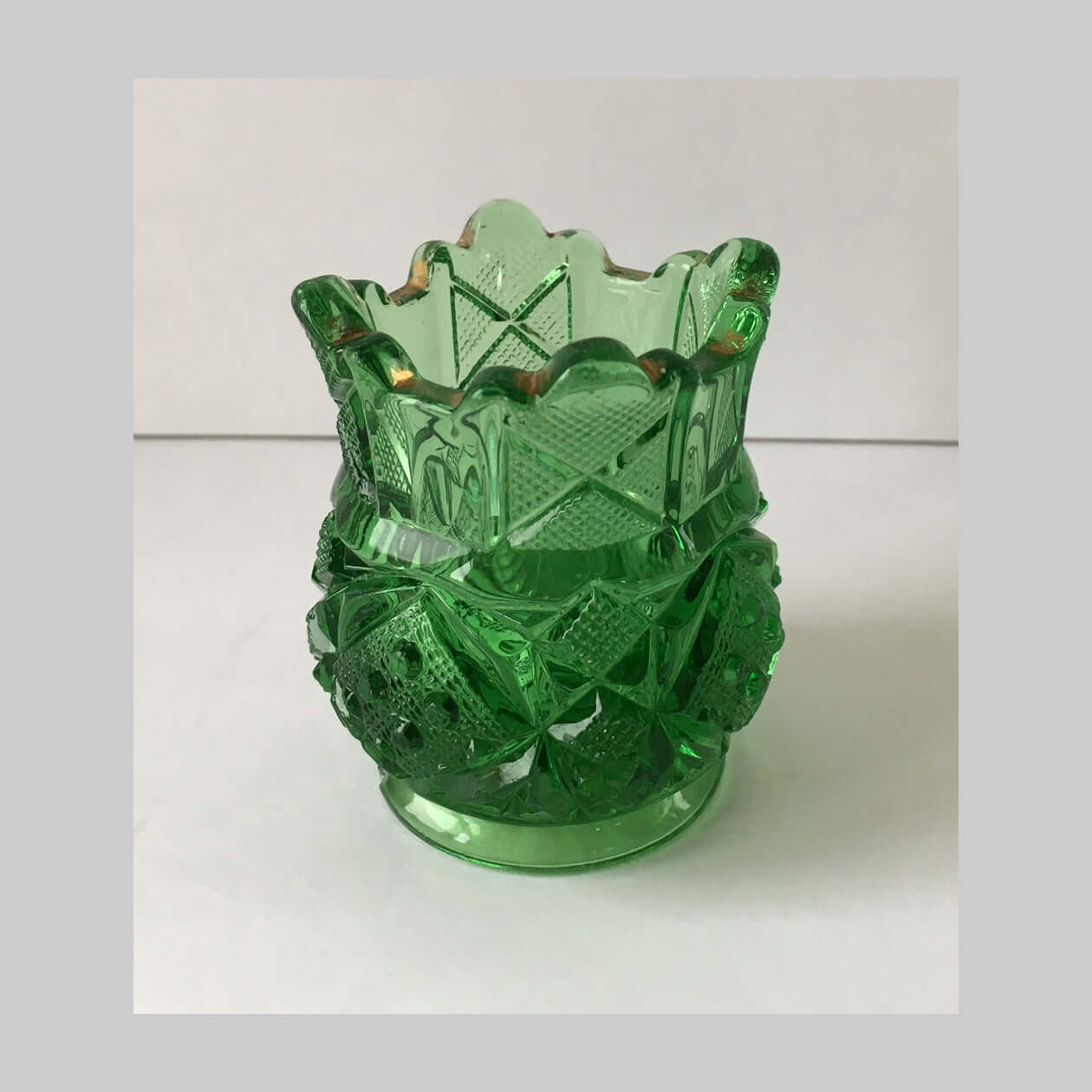 Antique green pressed glass toothpick holder in Sunbeam pattern.